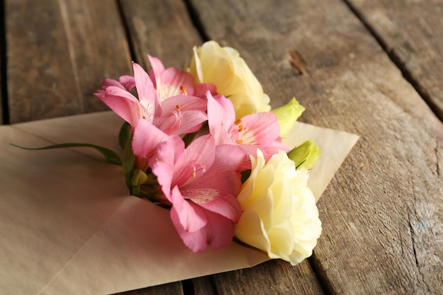 Witte eustoma en roze alstroemeria in envelop op houten achtergrond