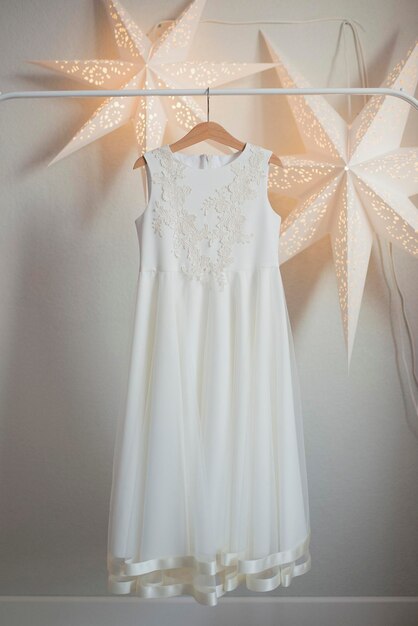 Witte feestelijke jurk hangend aan een houten hanger