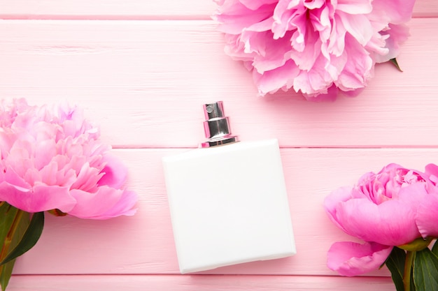 Witte fles parfum met roze bloem op roze achtergrond