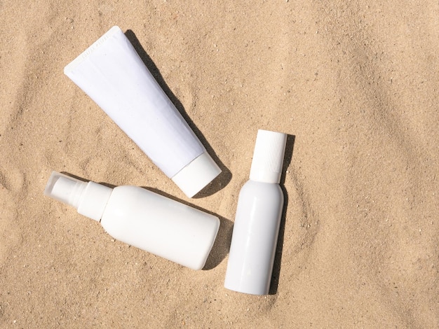 Witte flessen met cosmetische zonnefilters voor huidverzorging op het zand