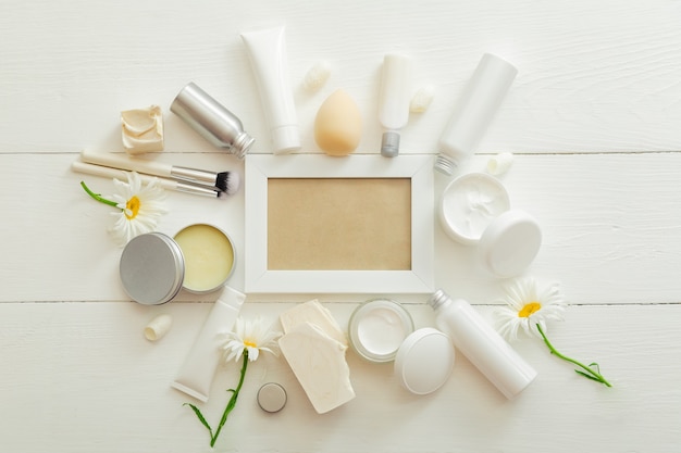 Witte frame set cosmetische producten in witte mockup verpakking op houten tafel bloemen, cosmetische tas. schoonheid huidverzorging haarbehandeling cosmetische vochtinbrengende crème body butter zeep. plat lag kopieerruimte.