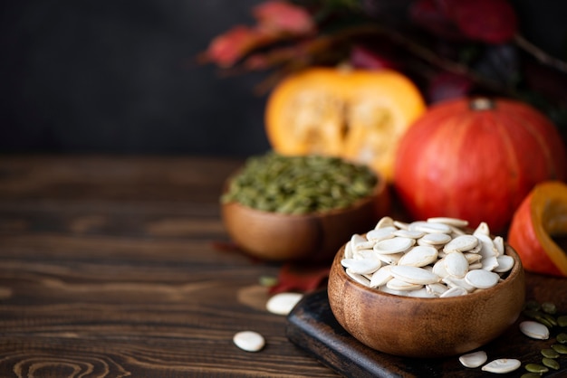 Witte gedroogde pompoenpitten en kleine pompoenen op een houten tafel