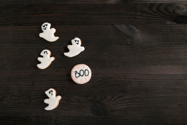 Witte gemberkoekjes in de vorm van geesten liggen op een donkere tafel voor halloween glimlachende koekjesruimte voor tekstbovenaanzicht