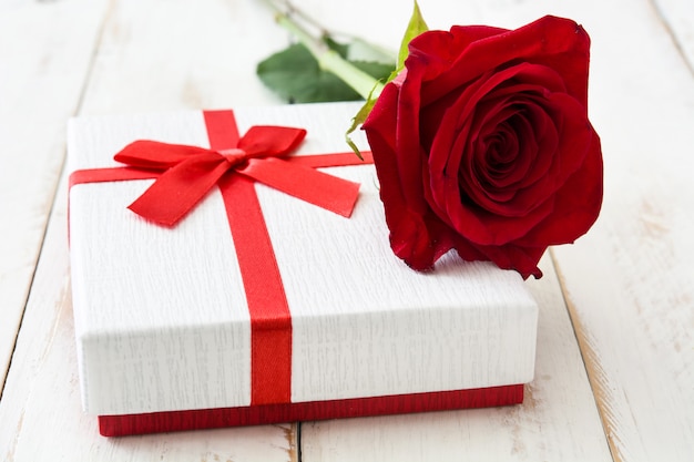 Witte geschenkdoos en rode rozen op witte houten tafel