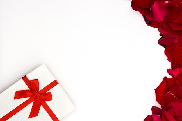 Witte geschenkdoos en rode rozenblaadjes op witte kopie ruimte