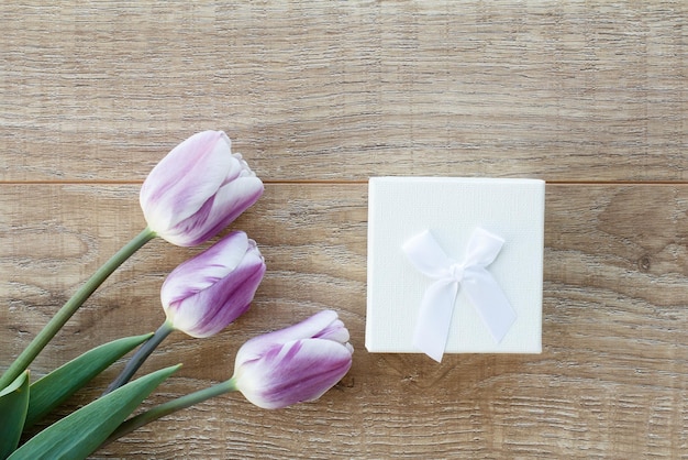 Witte geschenkdoos met prachtige tulpen op de houten planken Bovenaanzicht Concept van het geven van een geschenk