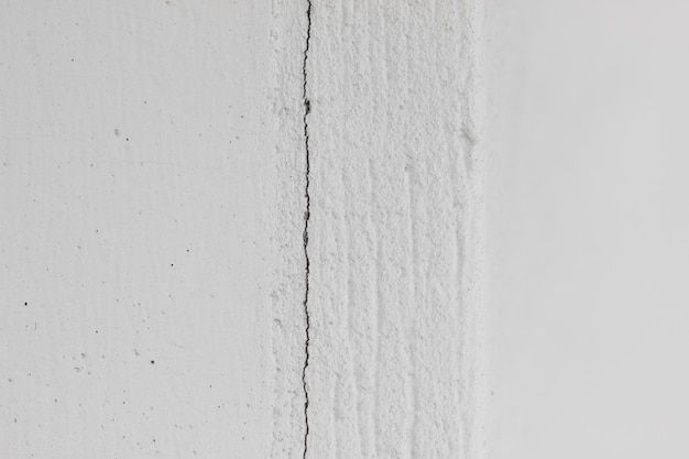 Witte getextureerde betonnen muur met stippen en verticale scheur horizontale foto