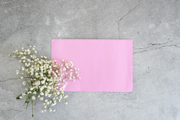 Witte gypsophila bloemen met roze envelop op blauwe achtergrond