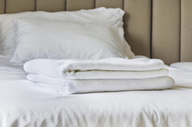 Witte handdoeken op bed in gastenkamer voor hotelklant gevouwen badstof handdoeken liggen op schoon wit bed