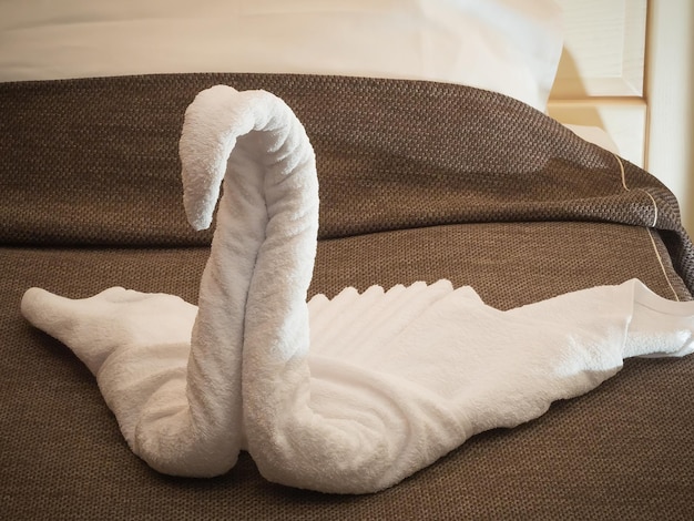 Foto witte handdoeken zijn gevouwen in een zwaanvorm op het hotelbed origami handdoek zwaan