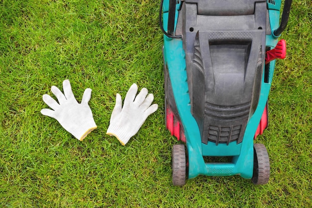 Witte handschoenen en een grasmaaier een close-up in het gras Een weergave van bovenaf Opruimservice