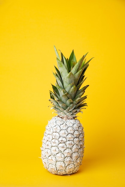 Witte hele verse ananas op tafel geplaatst in moderne studio op gele achtergrond