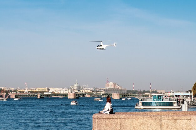 Witte helikopter van het stadsbestuur over de rivier de neva in st. petersburg.