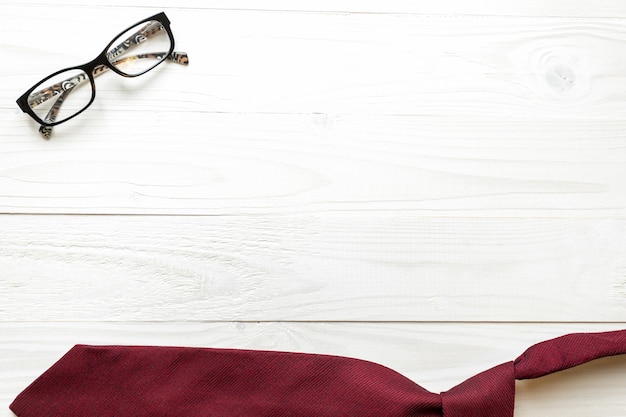 Witte houten achtergrond met rode stropdas en bril. Zakelijke achtergrond concept