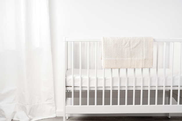 Witte houten babybedje in de kinderkamer