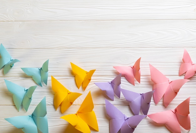 Foto witte houten oppervlak met heldere kleurrijke papieren origami vlinders met kopie ruimte voor uw tekst