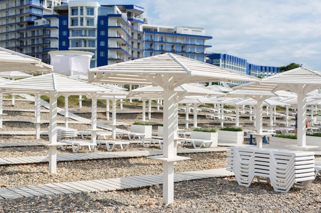 Witte houten parasols paden en ligstoelen aan de kust oceaan