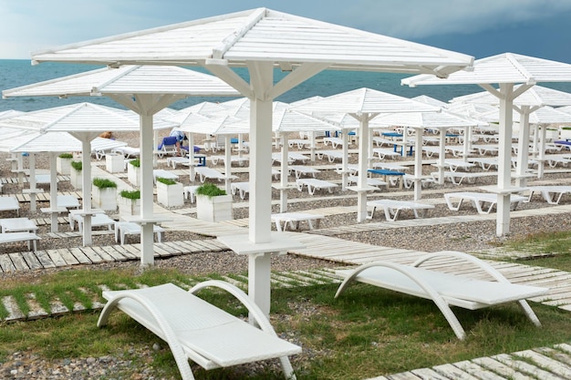 Witte houten parasols paden en ligstoelen aan de kust oceaan