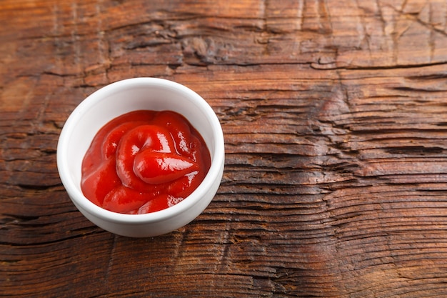 Foto witte juskom met ketchup op een houten tafel