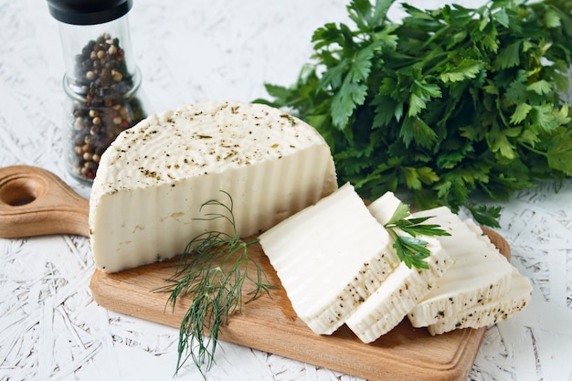 Witte kaas en kruiden op een houten bord op een witte achtergrond