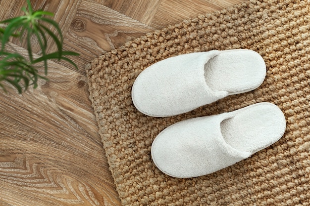 Witte kamerpantoffels op jute vloerkleed