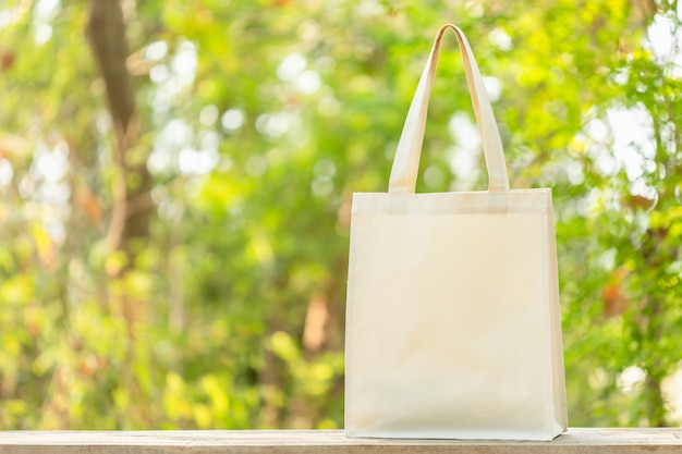 Witte katoenen tas op houten tafel met ruimte voor tekst of reclame. Katoenen tas kan gebruiken om te winkelen om plastic zak op groene natuur te vervangen