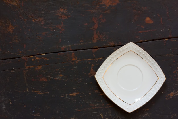 Witte keramische vierkante schotel op oude zwarte houten tafel.