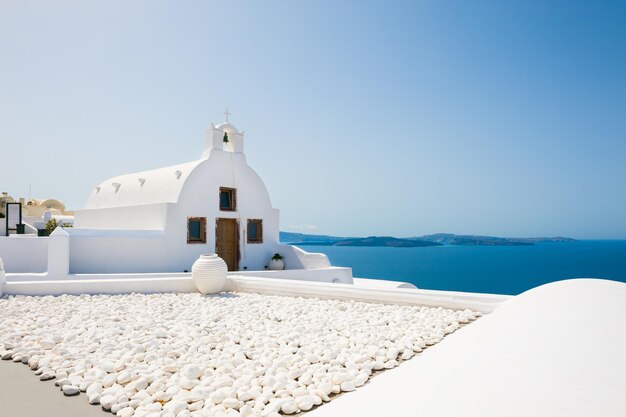 Witte kerk in oia-stad, santorini-eiland, griekenland. mooie zomerse landschap, uitzicht op zee.