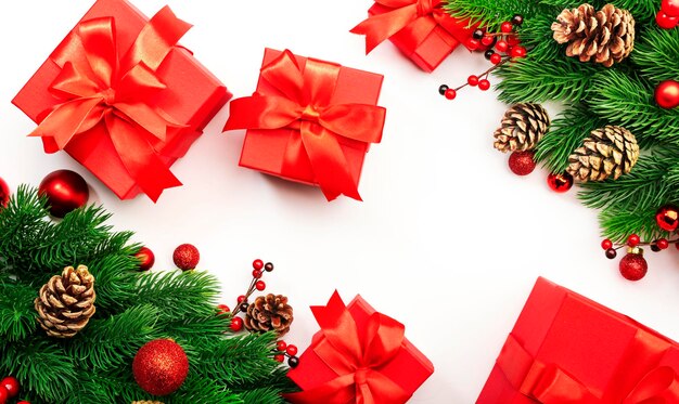 Witte Kerstmis en Nieuwjaar achtergrond met rode geschenkdozen kerstballen sparren takken kegels en bessen Bovenaanzicht frame met kopieerruimte