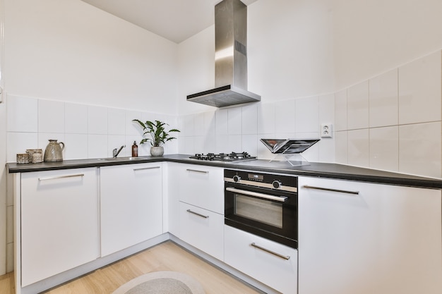 Witte keukenkasten met inbouwapparatuur gelegen nabij deur in lichte keuken van modern appartement