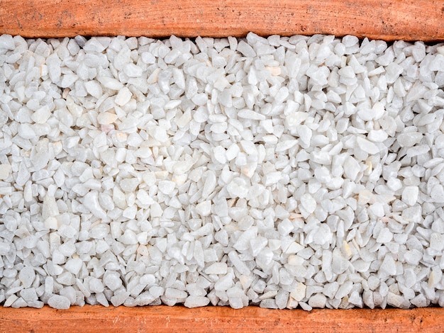 Witte kiezelsteenachtergrond. Steen grind textuur in terracotta pot, bovenaanzicht.