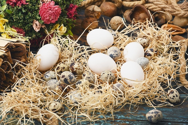 Witte kippeneieren en kwarteleitjes in de buurt van droge bloemen Eggs For Easter