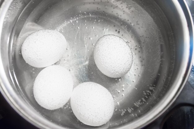 Witte kippeneieren koken in een pan