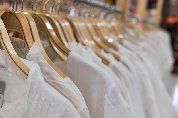 Witte kleding die aan houten rekken hangt Kleding voor vrouwen die aan hangers in een winkelcentrum hangt te koop