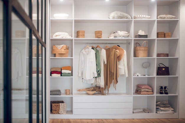 Witte kledingkast met kleding en schoenen op de planken