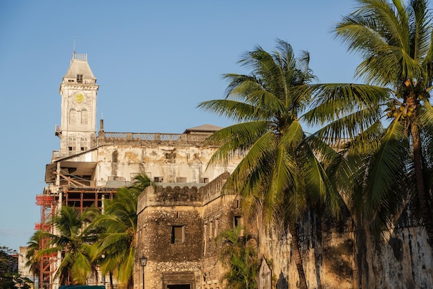 Witte klokkentoren en stenen fort tussen palmbomen in Stone Town. Zanzibar, Tanzania