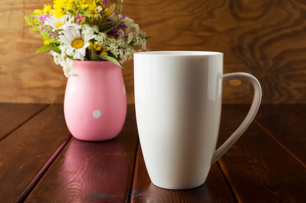 Foto witte koffie cappuccino mok met wilde bloemen in roze vaas