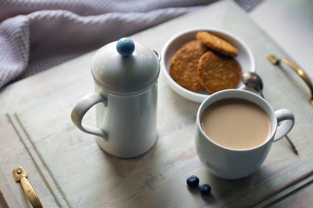 Witte koffiekopje met koekjes en theepot ontbijt met op houten tafel