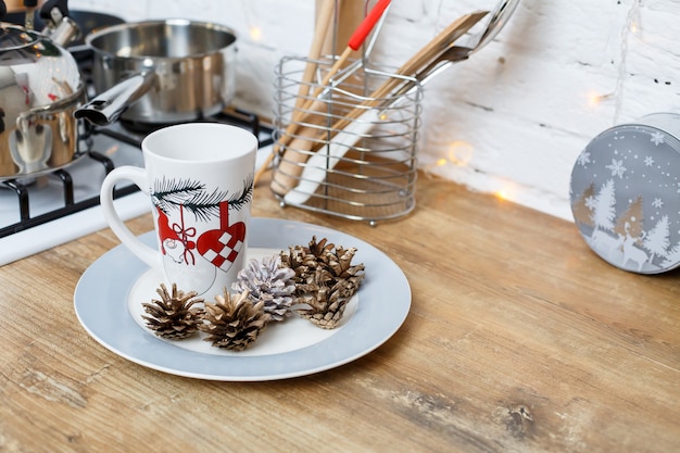 Witte koffiekopje op de keukentafel tegen de achtergrond van kerstversiering. stukjes op een bord