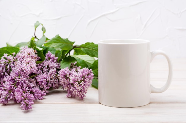 Witte koffiemok mockup met lila boeket op de houten tafel Lege mok mock up voor ontwerp promotie stijl sjabloon