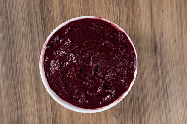 Witte Kom Braziliaanse Bevroren Acai Berry op een houten bureau Bovenaanzicht