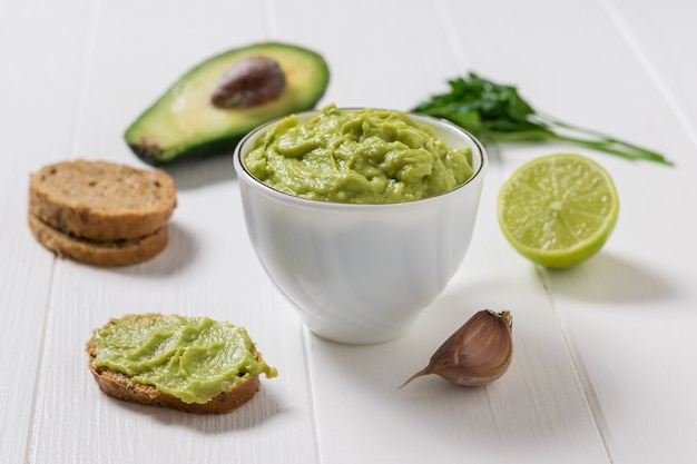 Witte kom gevuld met verse guacamole en ingrediënten om te koken. dieet vegetarisch mexicaans eten avocado. rauw eten.