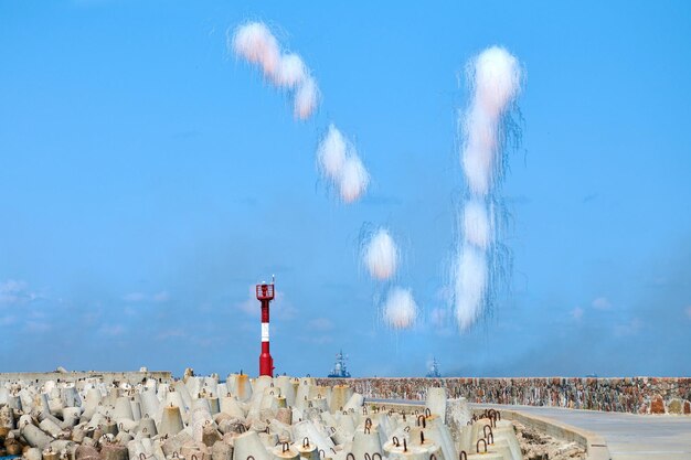 Witte koolstofvezelwolken die marine-torpedojagers verbergen voor anti-scheepsraketten. Lancering van antiraketten in de tijd van de militaire show, blauwe hemelachtergrond. Oorlogsschepen in gevechtstraining, brandweerschepen in de Oostzee