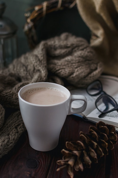 Witte kop cacao op een oude houten tafel met een onderhoudend boek en leesbril.