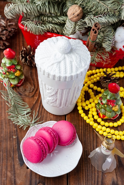 Witte kop en roze makarons met Kerstmisdecoratie op houten achtergrond