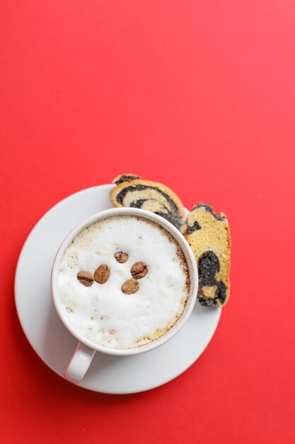 witte kop geurige koffie met schuim en koekjes op een rode achtergrond