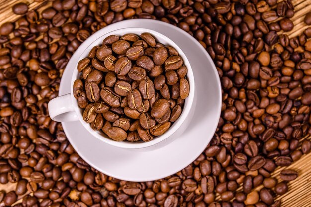 Witte kop gevuld met koffiebonen op houten tafel Bovenaanzicht