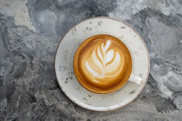 Witte kop hete latte koffie met mooie melkschuim latte art textuur geïsoleerd op heldere marmeren achtergrond. Bovenaanzicht, kopieer ruimte. Reclame voor cafémenu.