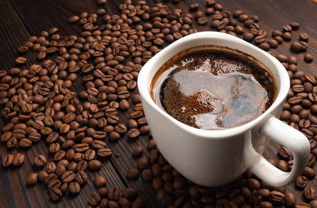 Foto witte kop koffie met bonen op een donkere houten tafel