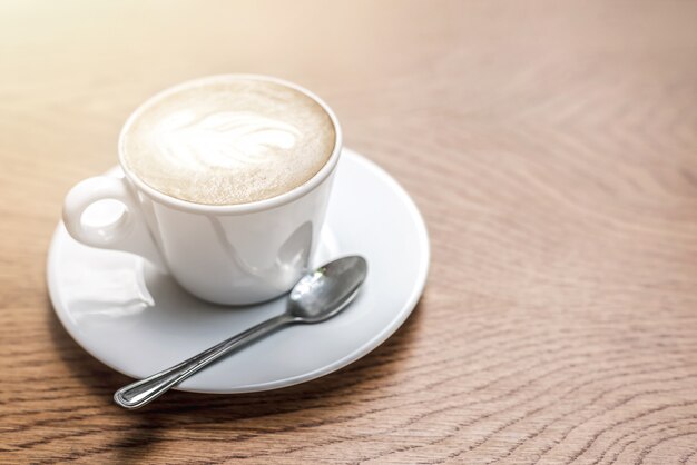 Witte kop koffie met kunst op houten tafel